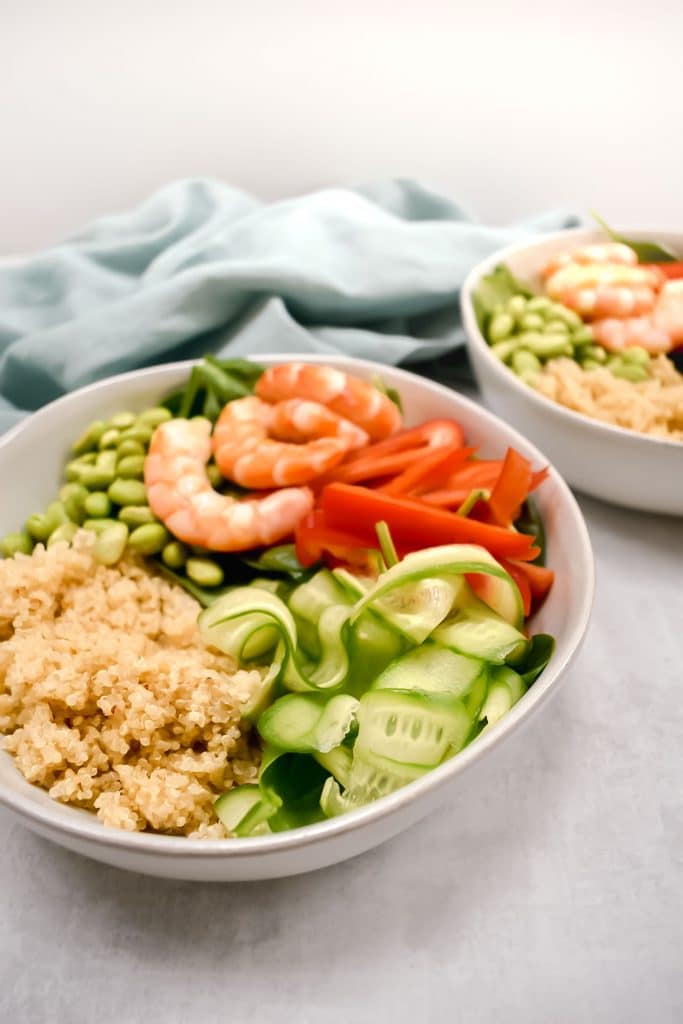 45 degreen angle of shrimp and quinoa power bowl on grey background with blue linen