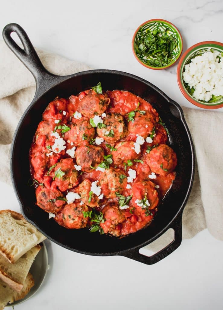 overhead shot of greek turkey meatballs with feta cheese in cast iron pan