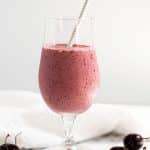 cherry vanilla smoothie in milkshake glass with straw on marble background