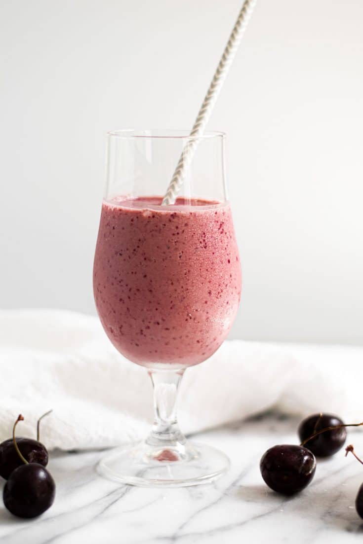 cherry vanilla smoothie in milkshake glass with straw on marble background