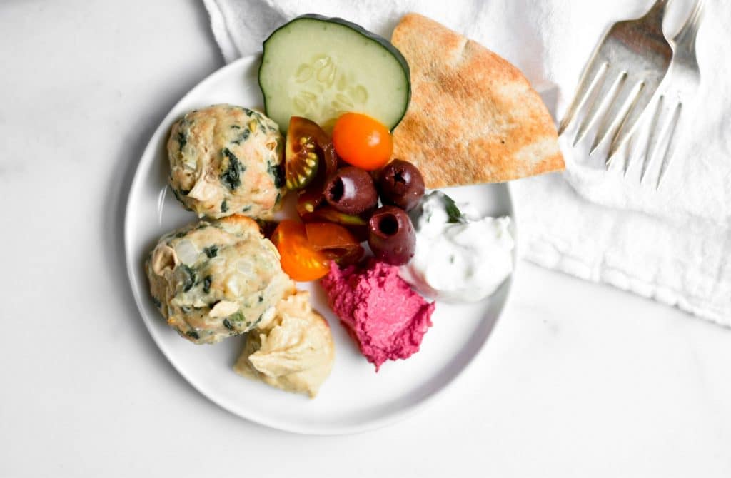 small plate with meatballs and Greek dips on it with forks next to plate