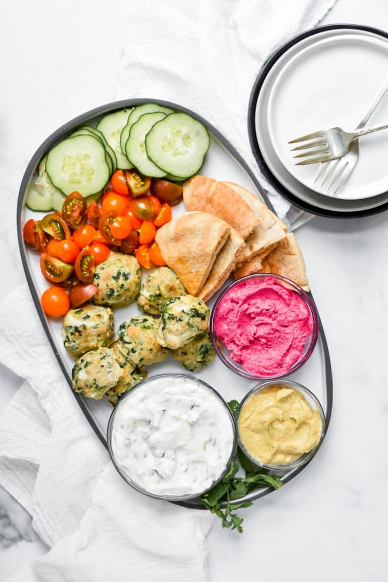 overhead shot of meatball platter with dips and veggies on white background