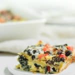 slice of casserole on small white plate with baking dish in background