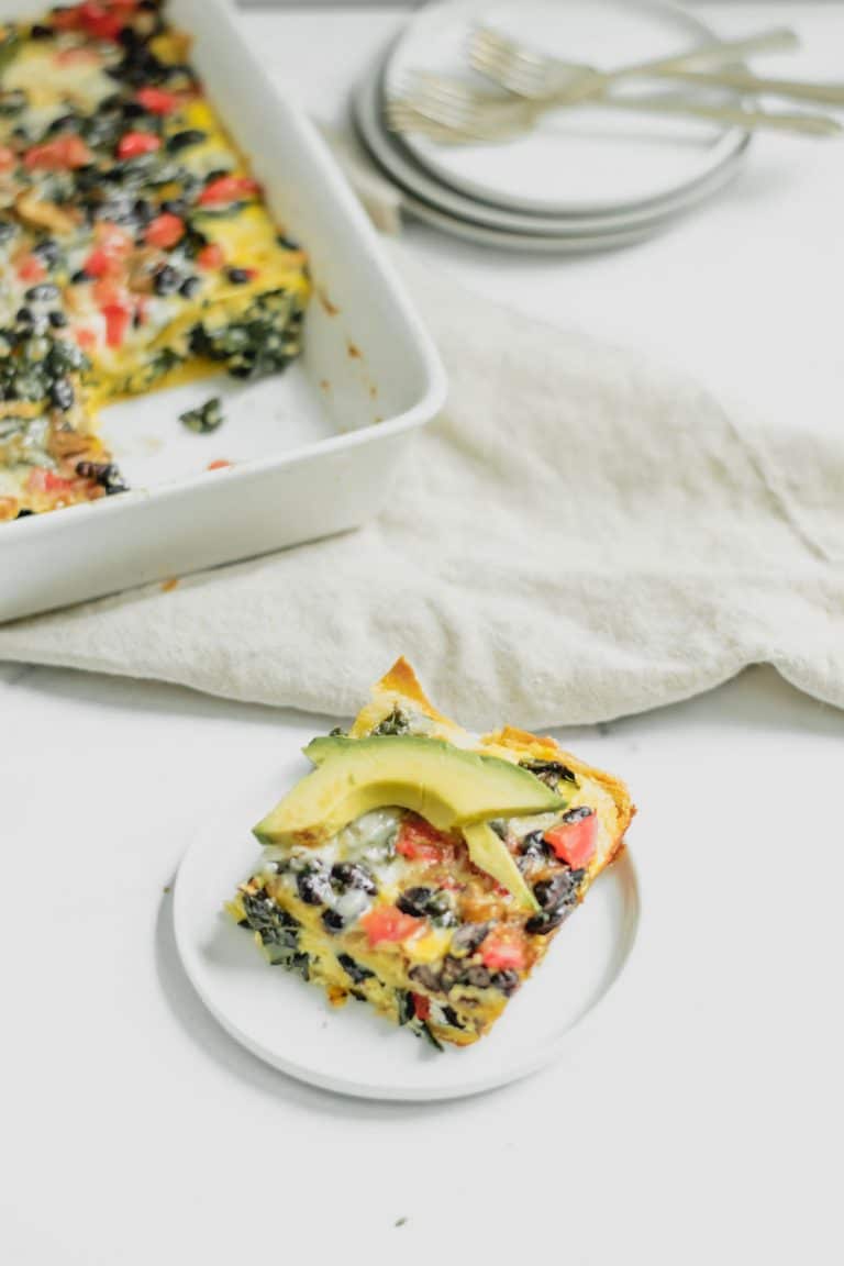 slice of casserole topped with avocado slices and dish in background