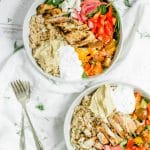 overhead shot of mediterranean grain bowls in white bowls with 2 forks