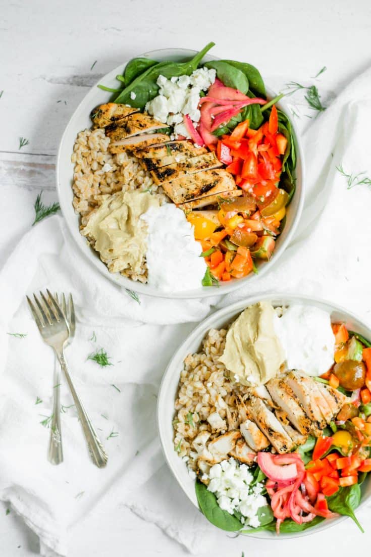 overhead shot of mediterranean grain bowls in white bowls with 2 forks