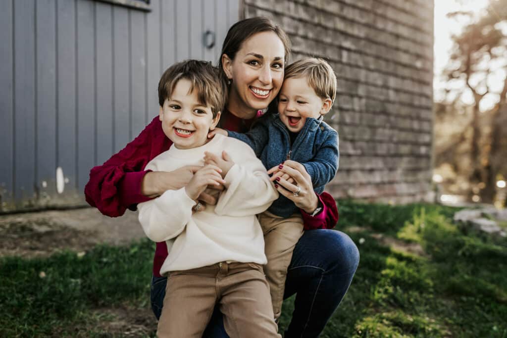 image of sarah with her two boys in a field with a barn in the background