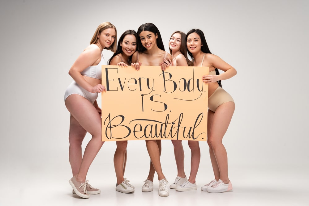5 women holding a sign that says every body is beautiful