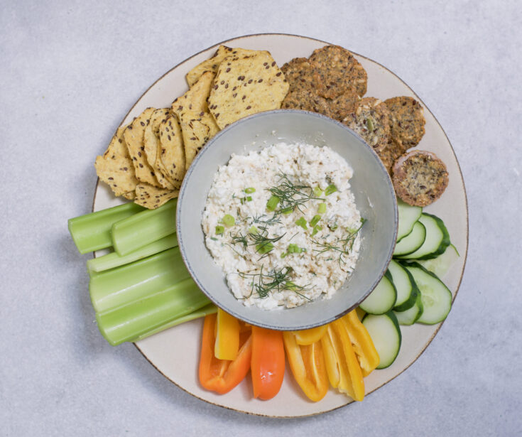 overhead view of the buffalo chicken cottage cheese dip on a plate with veggies and chips
